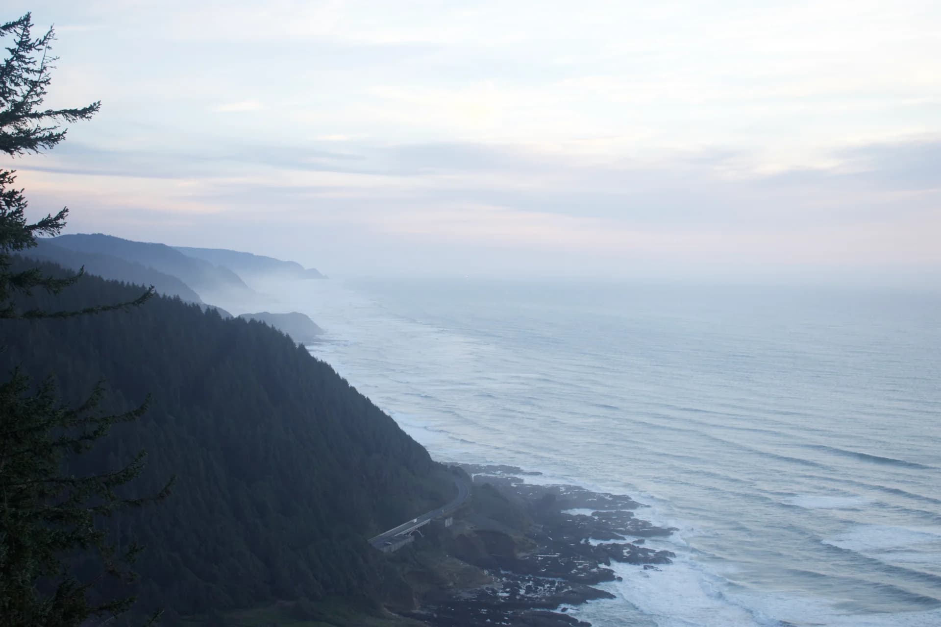 A coastal highway beneath forested cliffs