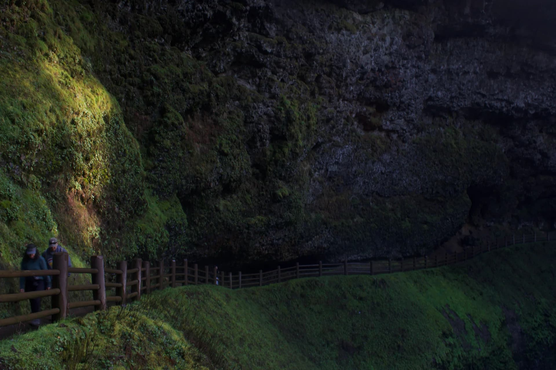 Hikers on a path beneath a rocky overhang